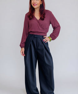 Model draagt Bob & Bill Dean marineblauwe high-waist pantalon met plooien en wijde pijpen van polyester en elastaan.