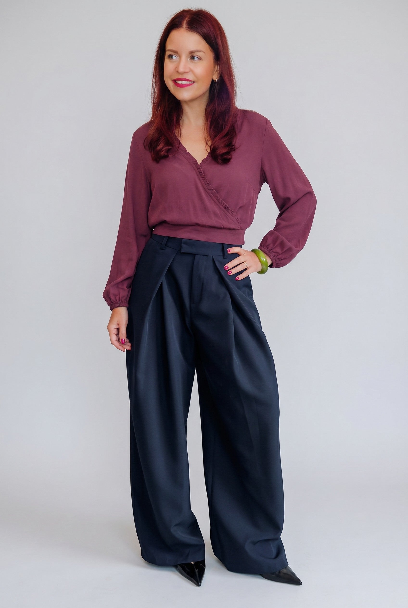 Model draagt Bob & Bill Dean marineblauwe high-waist pantalon met plooien en wijde pijpen van polyester en elastaan.