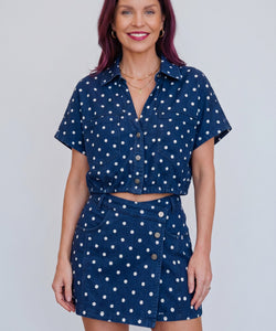 Model draagt Bob & Bill LISSI navy denim blouse met witte stippenprint, korte mouwen en knoopsluiting.