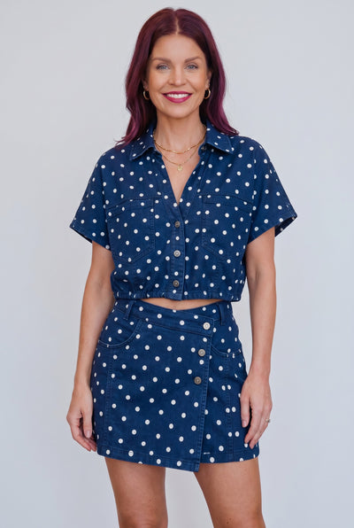 Model draagt Bob & Bill LISSI navy denim blouse met witte stippenprint, korte mouwen en knoopsluiting.