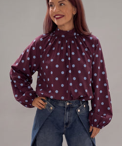 Bob & Bill bordeaux polka dot blouse with long puff sleeves, high collar, and relaxed fit worn by a smiling woman.