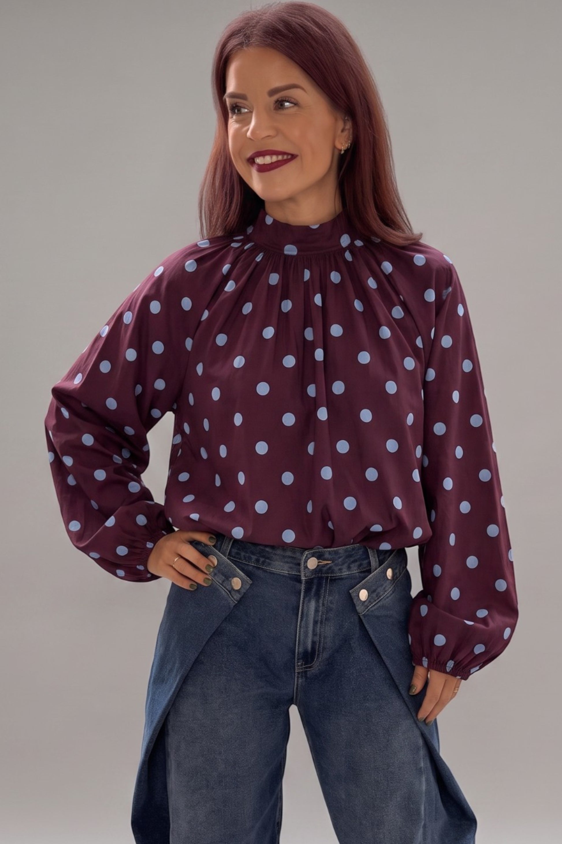 Bob & Bill bordeaux polka dot blouse with long puff sleeves, high collar, and relaxed fit worn by a smiling woman.