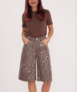 Bob & Bill Yuna brown jorts with a white paisley print, mid-high waist, and pockets worn with a brown t-shirt.