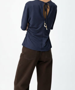 Bob & Bill ISLA TEE in marineblauw, een losvallende viscose top met open rug, strikdetail, pofmouwen en schelpjes aan de achterkant.