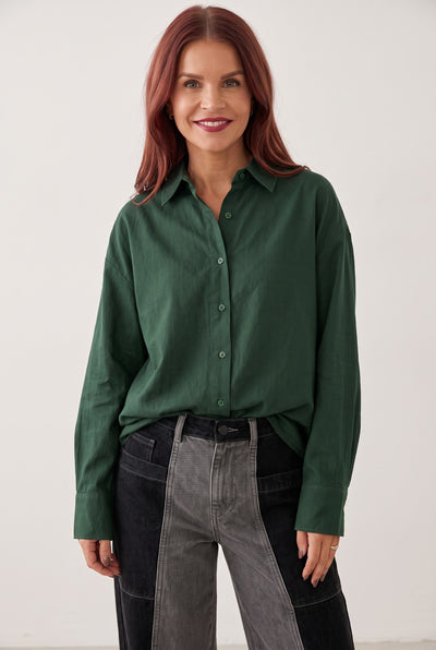 Model wearing a Bob & Bill dark green loose fit Nancy blouse with long sleeves and a classic collar