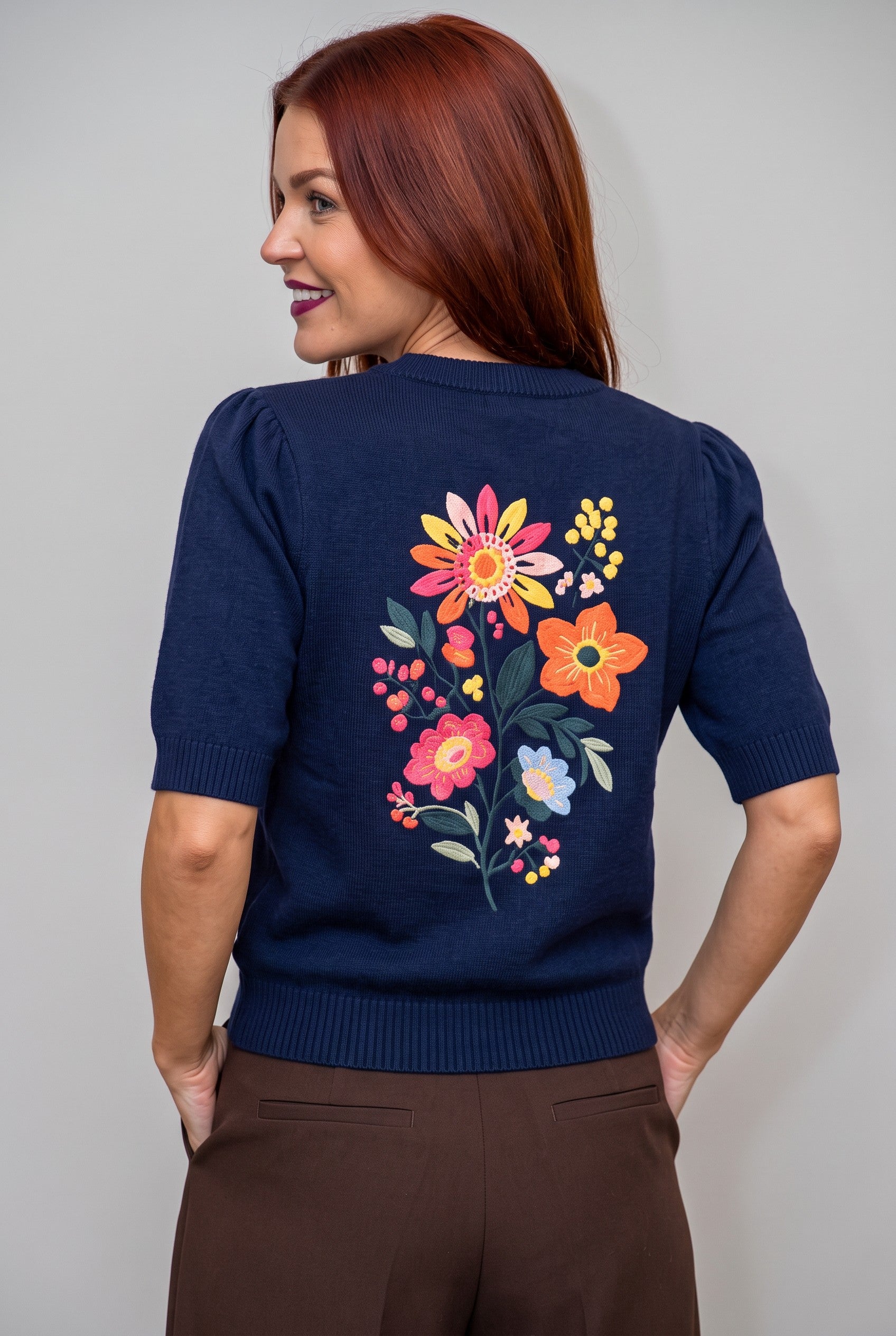 Bob & Bill navy knit sweater with short sleeves and vibrant floral embroidery on the back, worn by a woman.