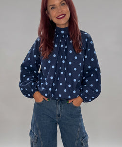Bob & Bill navy polyester blouse with light blue polka dots, high collar, and puff sleeves worn with cargo jeans.