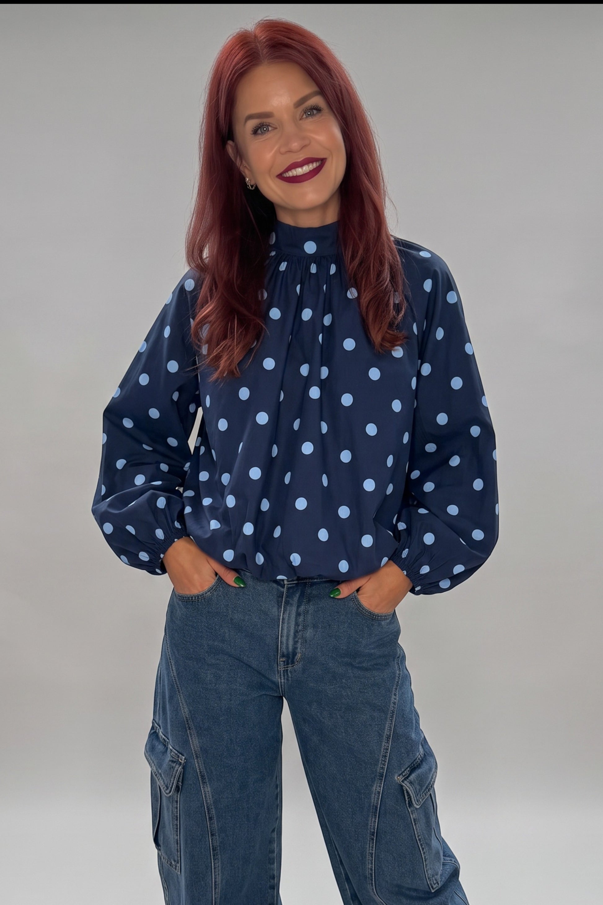 Bob & Bill navy polyester blouse with light blue polka dots, high collar, and puff sleeves worn with cargo jeans.